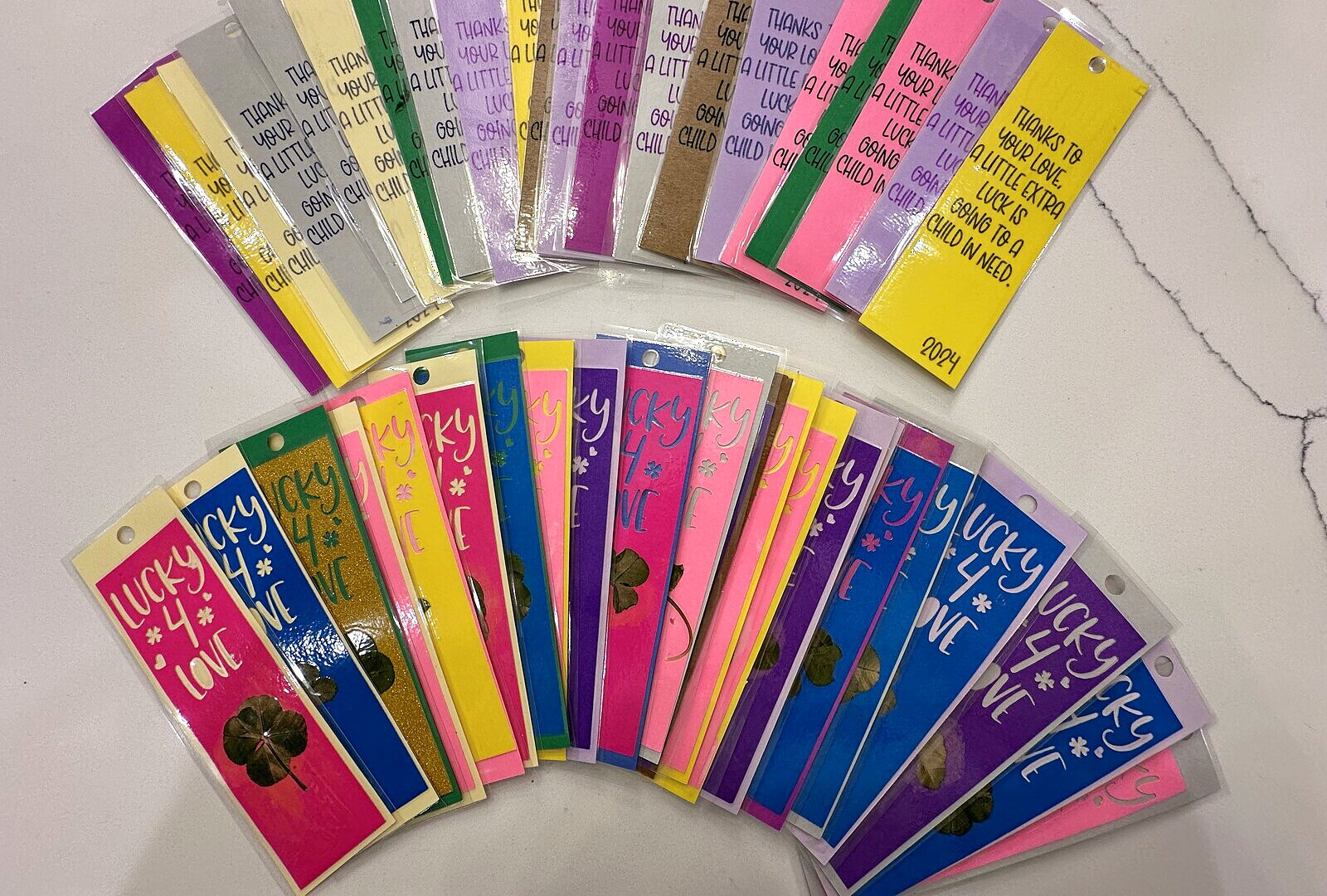 A fan of handmade Lucky4Love bookmarks in pink, purple, blue and yellow, each with a real pressed four-leaf clover