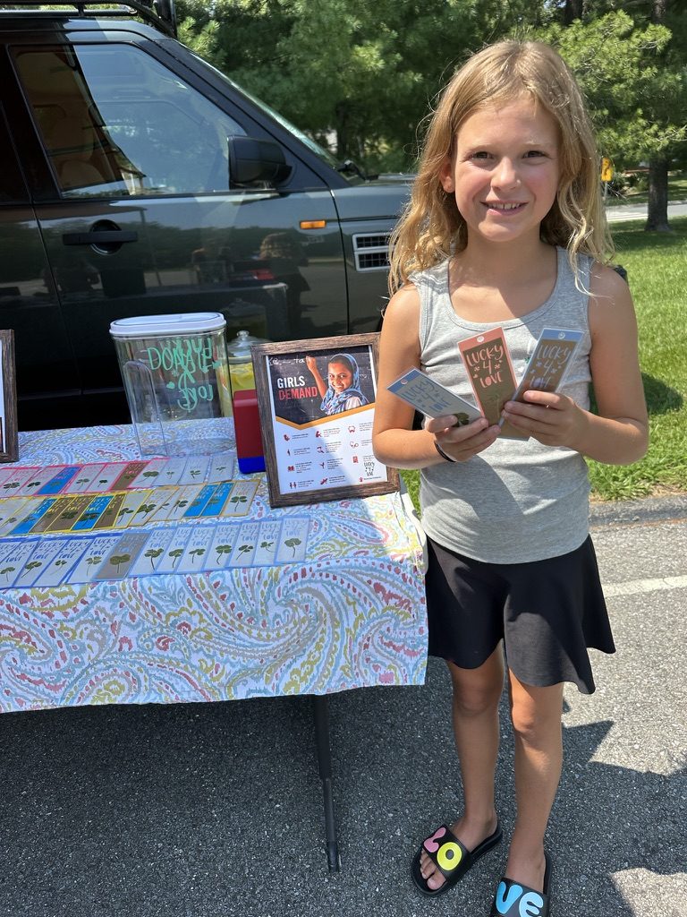 A sister holding packs of clover bookmarks at the stand